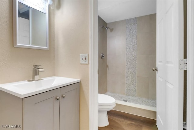 bathroom with vanity, wood finished floors, toilet, and a shower stall