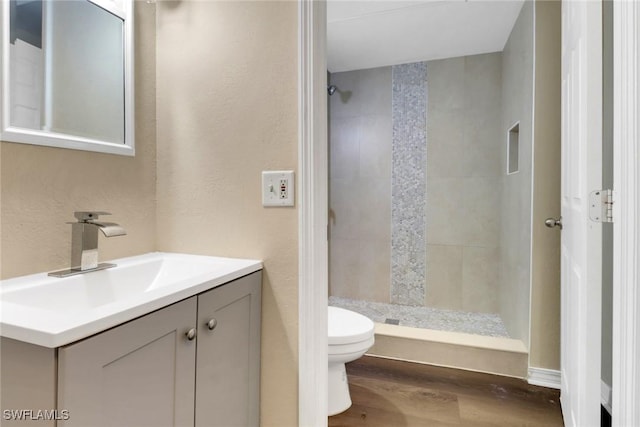 full bath with a textured wall, toilet, wood finished floors, vanity, and a shower stall