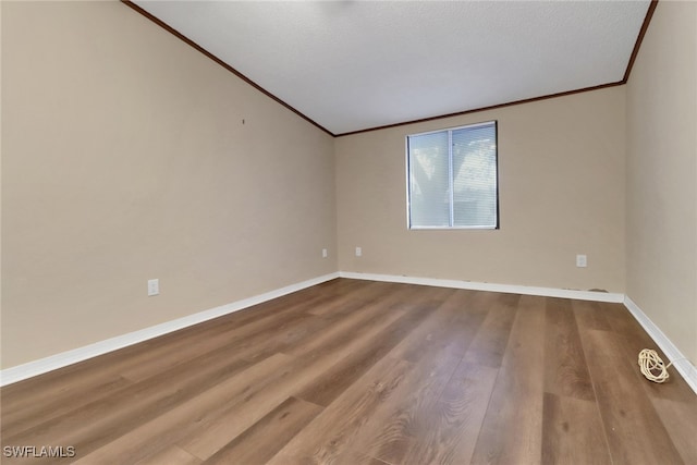 unfurnished room with crown molding, a textured ceiling, baseboards, and wood finished floors