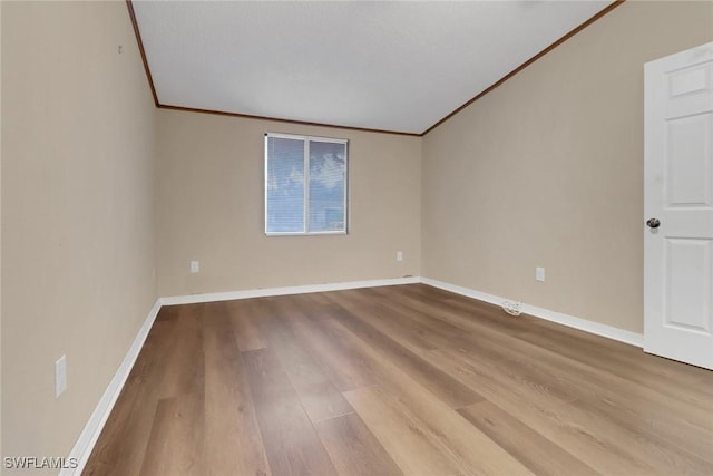 spare room featuring baseboards, ornamental molding, and light wood-style floors