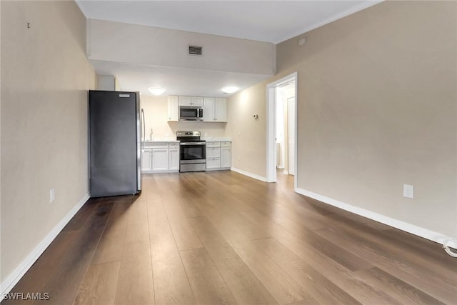 kitchen featuring visible vents, white cabinets, appliances with stainless steel finishes, wood finished floors, and light countertops