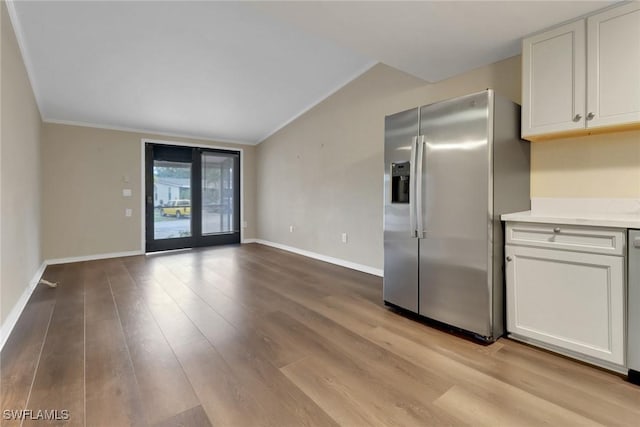 kitchen with light countertops, white cabinets, stainless steel fridge, and light wood finished floors