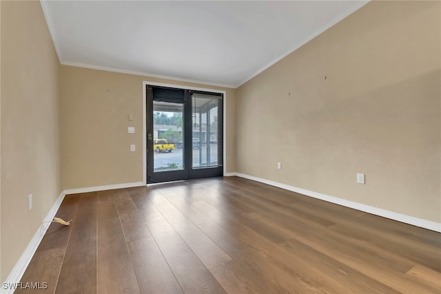 spare room featuring ornamental molding, baseboards, and wood finished floors