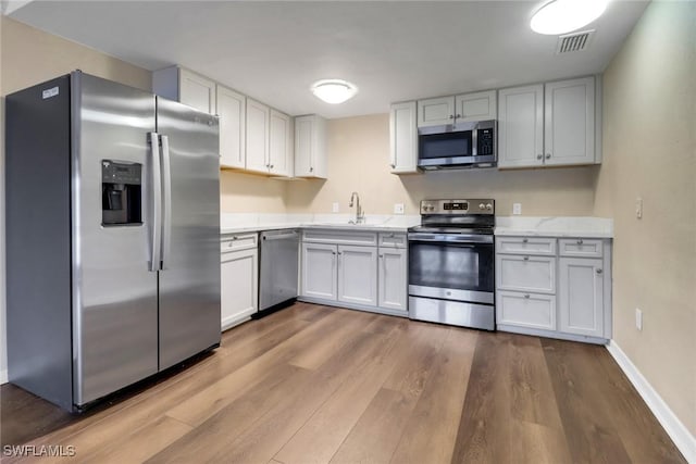 kitchen with a sink, visible vents, white cabinetry, appliances with stainless steel finishes, and light wood finished floors