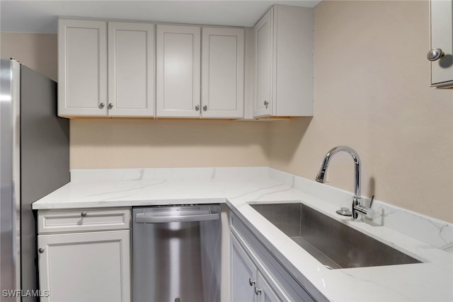 kitchen with appliances with stainless steel finishes, a sink, and white cabinetry