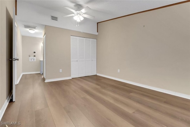 unfurnished bedroom with ceiling fan, light wood-style flooring, visible vents, baseboards, and a closet