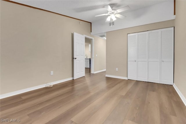 unfurnished bedroom featuring wood finished floors, a ceiling fan, visible vents, baseboards, and a closet