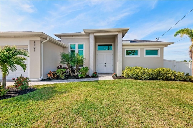 view of front facade featuring a front lawn, an attached garage, and stucco siding