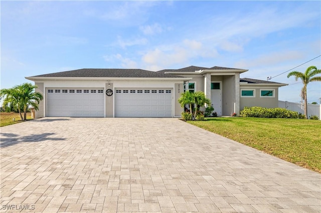 prairie-style home with a garage, a front lawn, decorative driveway, and stucco siding