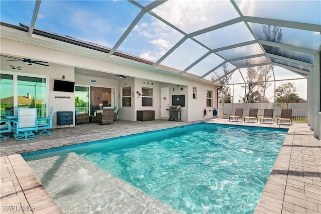 view of swimming pool with glass enclosure, a fenced in pool, a ceiling fan, and a patio