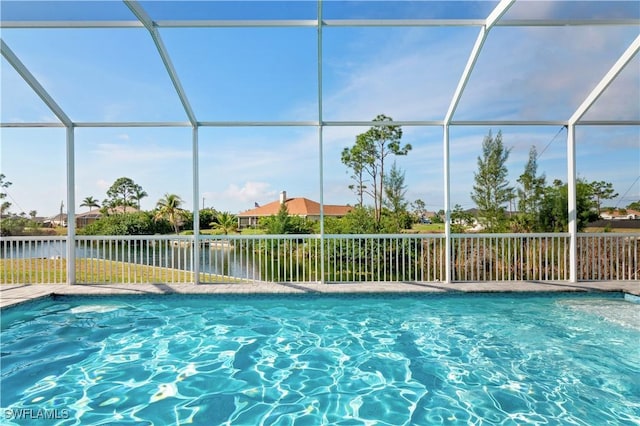 view of pool with a fenced in pool, glass enclosure, and a water view