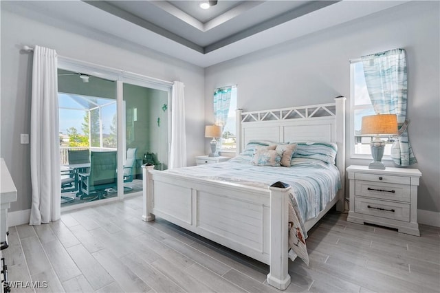 bedroom featuring multiple windows, wood tiled floor, a sunroom, and access to exterior