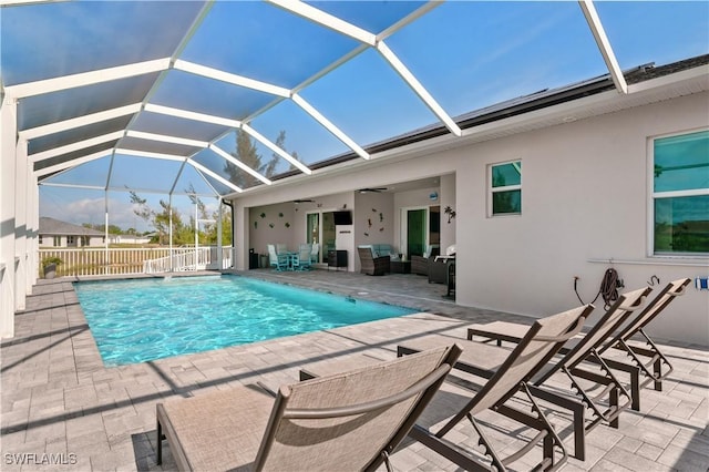 view of swimming pool featuring glass enclosure, fence, a ceiling fan, a fenced in pool, and a patio area