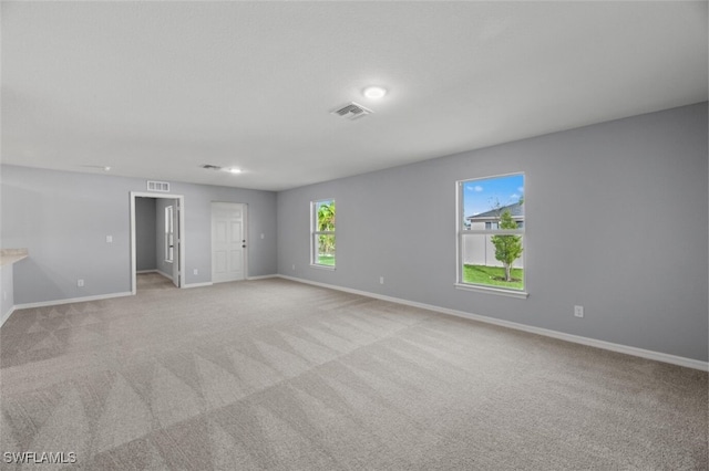 spare room featuring light carpet, visible vents, and baseboards