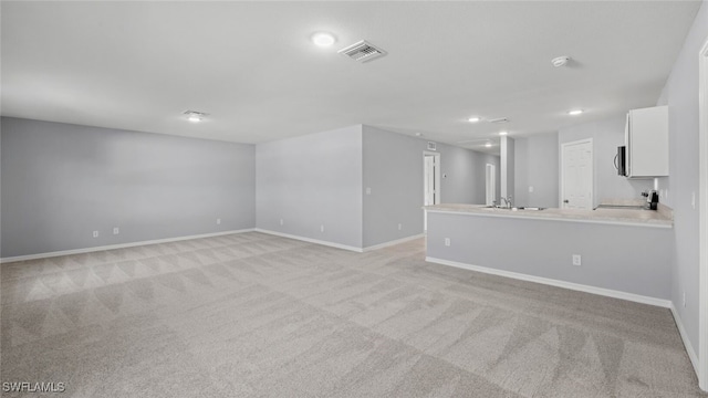 interior space featuring light carpet, a sink, visible vents, and baseboards