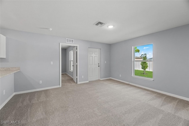 empty room featuring light carpet, visible vents, and baseboards