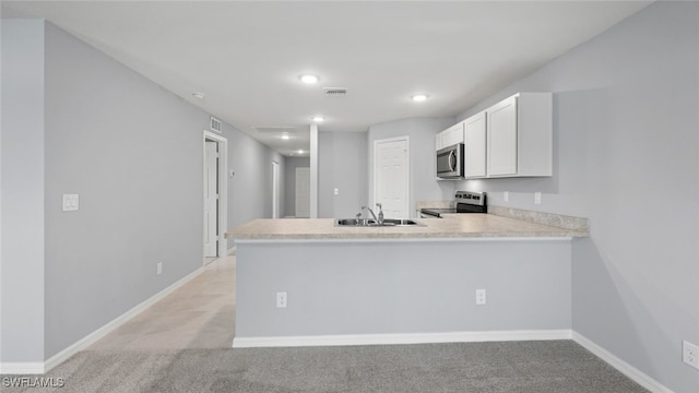 kitchen with light countertops, appliances with stainless steel finishes, white cabinetry, a sink, and a peninsula