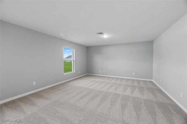 empty room featuring light colored carpet, visible vents, and baseboards