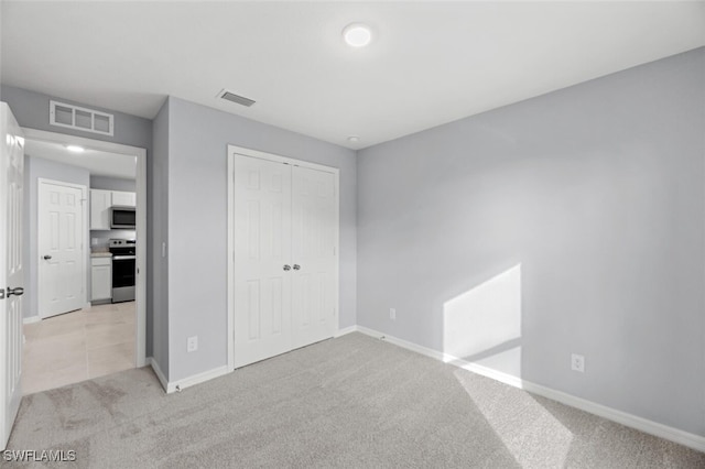 unfurnished bedroom with light carpet, a closet, visible vents, and baseboards