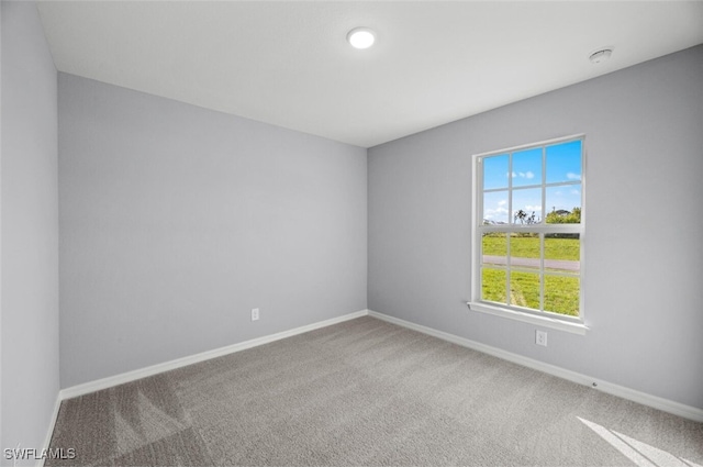 unfurnished room featuring carpet and baseboards