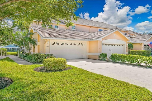 view of front of property with an attached garage, a tile roof, concrete driveway, stucco siding, and a front yard