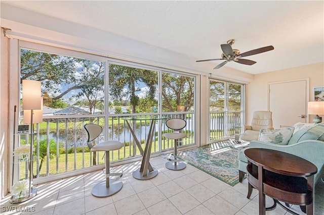 sunroom featuring a water view and a ceiling fan