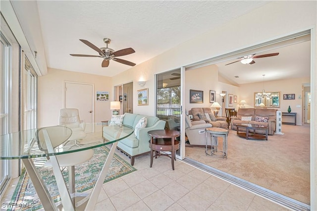 living area with light tile patterned floors, light carpet, vaulted ceiling, a textured ceiling, and ceiling fan with notable chandelier