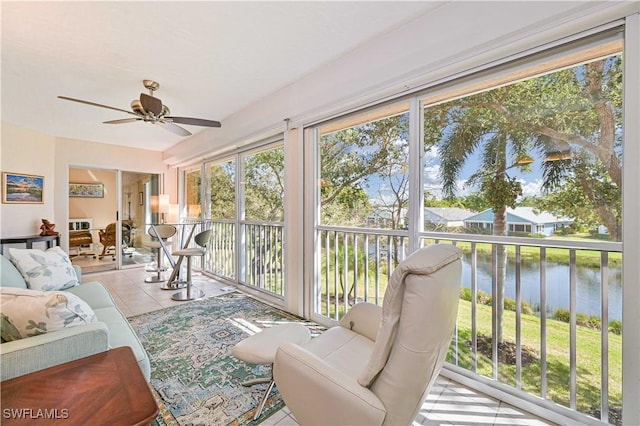 sunroom / solarium featuring ceiling fan and a water view