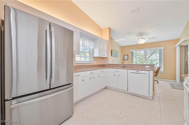 kitchen featuring dishwasher, freestanding refrigerator, a peninsula, white cabinetry, and a wealth of natural light