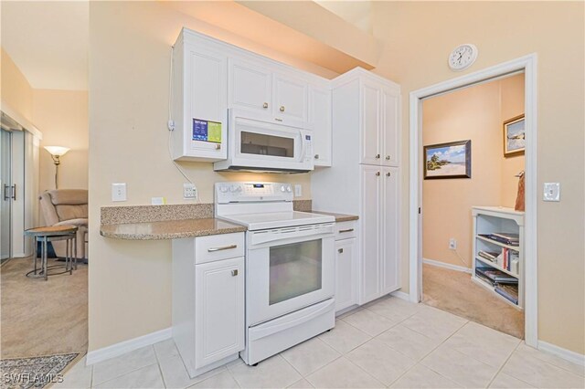 kitchen featuring white appliances, light tile patterned floors, baseboards, white cabinets, and light colored carpet