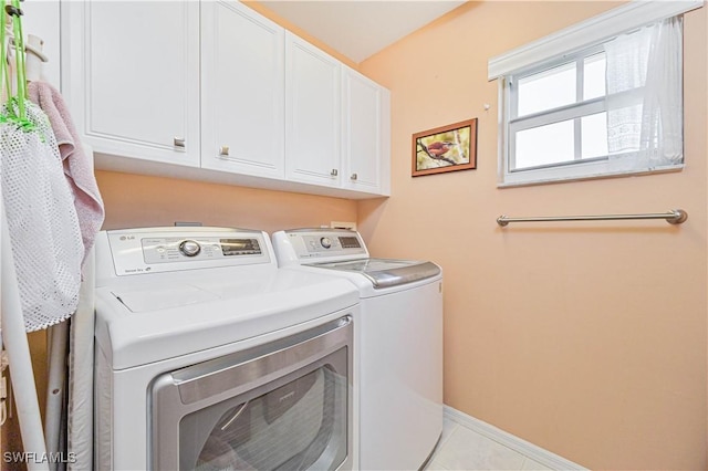 laundry area featuring tile patterned flooring, baseboards, cabinet space, and washing machine and clothes dryer