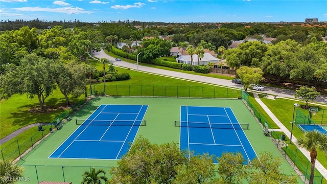 view of tennis court featuring fence and a lawn