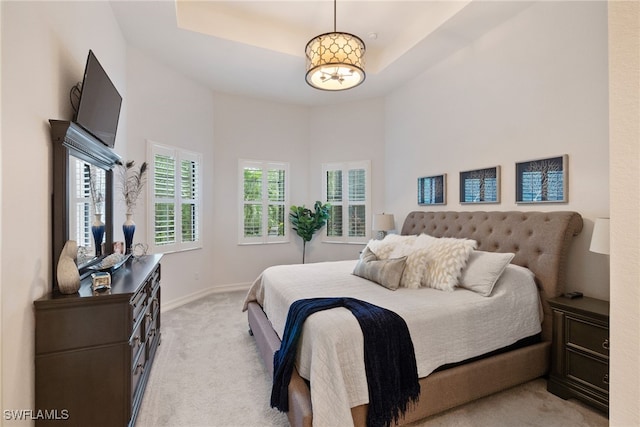 bedroom with baseboards, a high ceiling, a tray ceiling, and light colored carpet