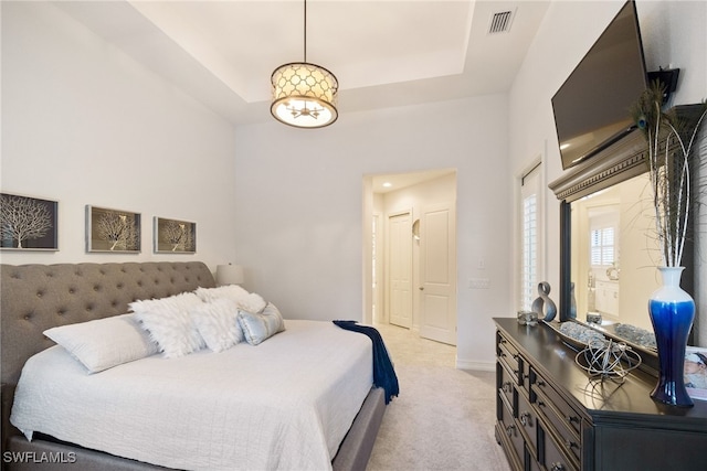 bedroom featuring a raised ceiling, light colored carpet, visible vents, and baseboards