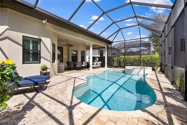 view of swimming pool featuring a pool with connected hot tub, glass enclosure, a patio, and ceiling fan