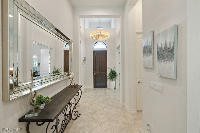 foyer featuring an inviting chandelier, a high ceiling, baseboards, and a wealth of natural light