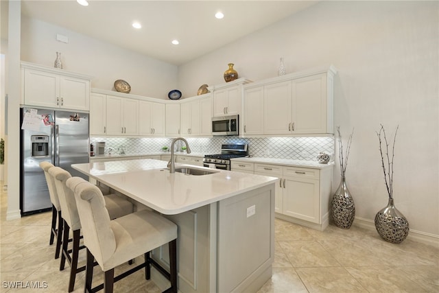 kitchen with a center island with sink, light countertops, appliances with stainless steel finishes, white cabinetry, and a sink