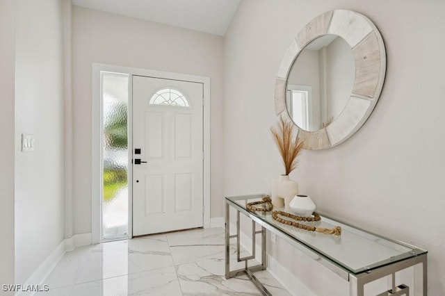 foyer entrance with marble finish floor and baseboards