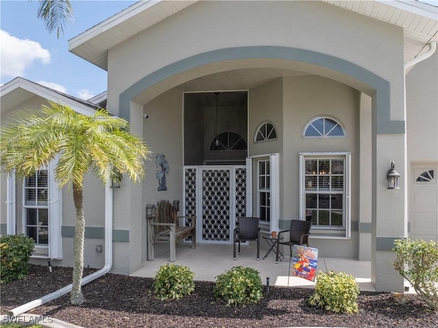 doorway to property with a porch and stucco siding