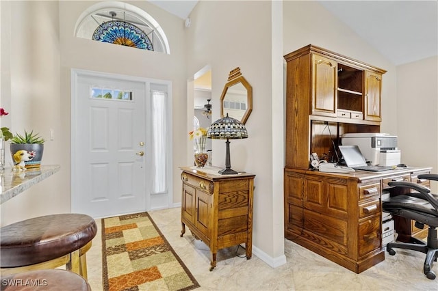 foyer entrance featuring baseboards and vaulted ceiling