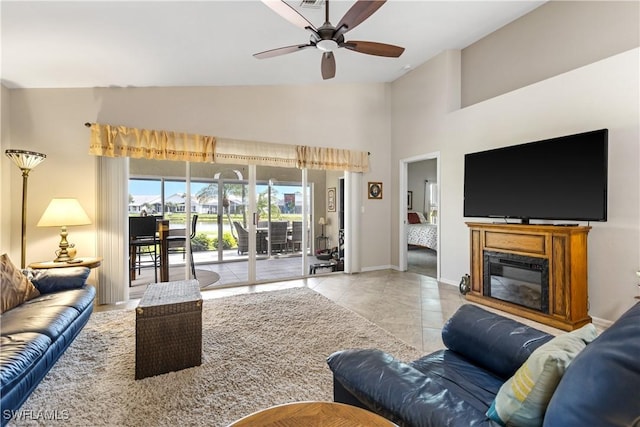 tiled living area featuring ceiling fan, a glass covered fireplace, visible vents, and baseboards