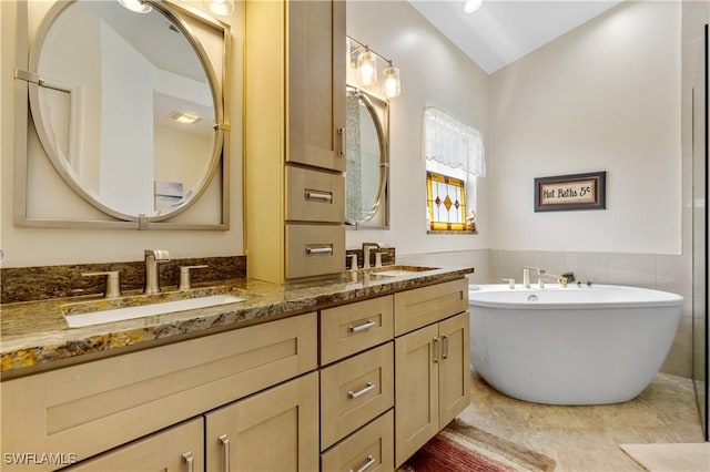 full bathroom with a sink, a freestanding bath, and double vanity