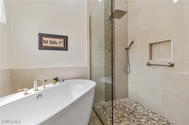 full bath with a tile shower, tile walls, and a freestanding bath