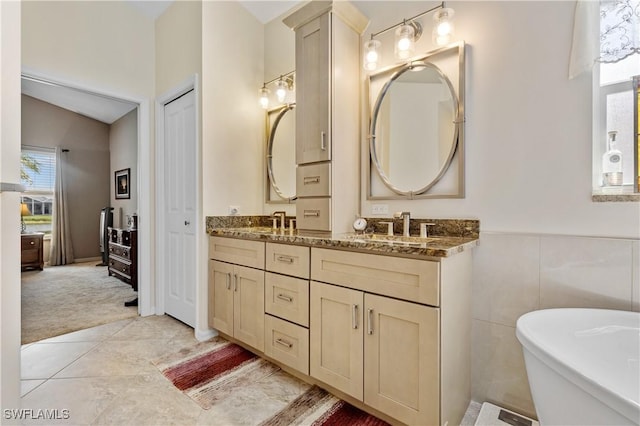 full bath with double vanity, a freestanding bath, a sink, and tile patterned floors