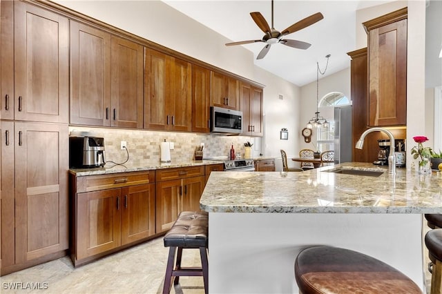 kitchen featuring a peninsula, a sink, a kitchen breakfast bar, appliances with stainless steel finishes, and backsplash