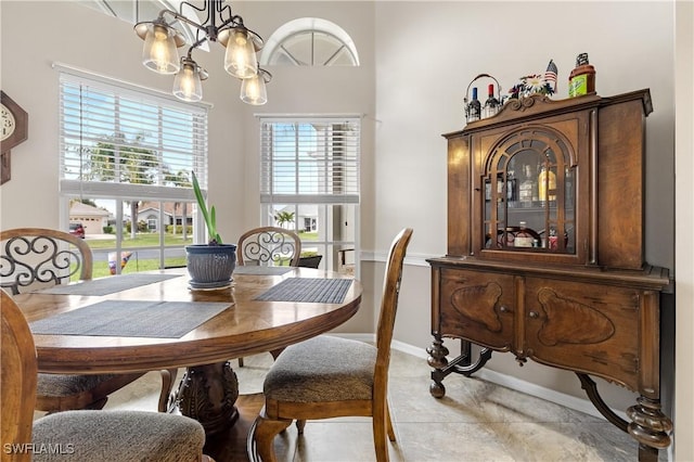 dining area featuring baseboards, light tile patterned flooring, and a notable chandelier