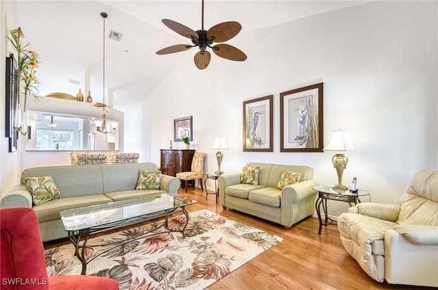 living room featuring high vaulted ceiling, visible vents, wood finished floors, and ceiling fan with notable chandelier