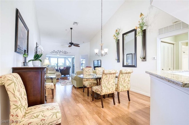 dining area featuring ceiling fan with notable chandelier, high vaulted ceiling, visible vents, and light wood-style floors