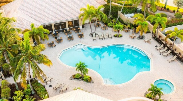 community pool featuring a patio, outdoor dining area, and a sunroom