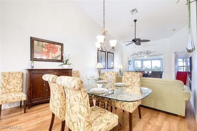 dining area with high vaulted ceiling, visible vents, and light wood-style flooring